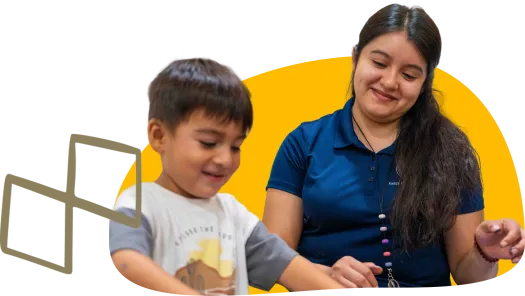 child sitting next to adult both looking down working on a project