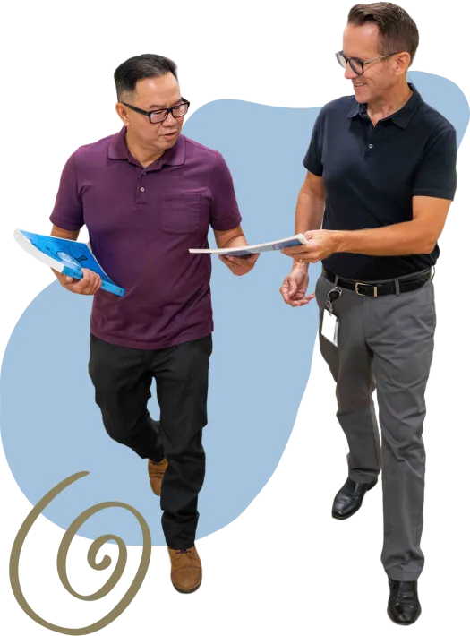 two people standing looking at notebooks