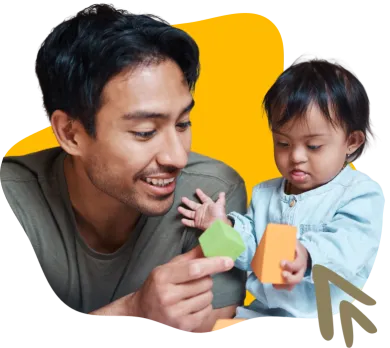 Person wearing a green shirt playing with an infant holding blocks