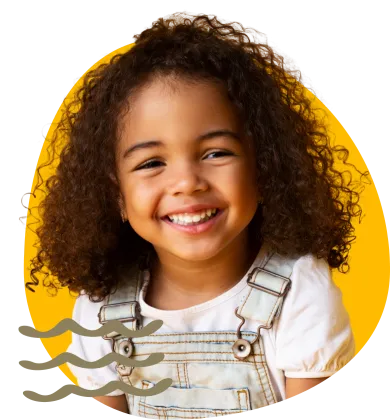 Young girl smiling wearing a white shirt and overalls